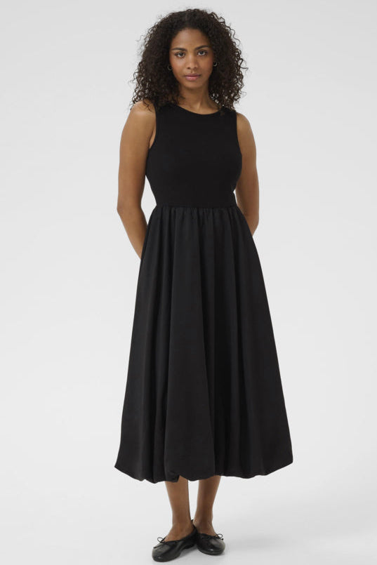 A model wearing a sleeveless, midi-length black dress with a square neckline, tank-style top, and a bubble hem.