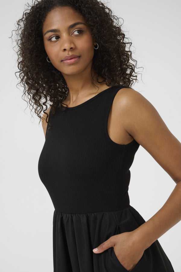 Woman wearing a black sleeveless top and black skirt on a white background