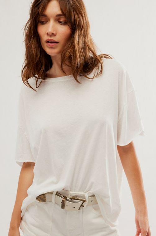 A woman wearing a loose white short-sleeve t-shirt and matching white shorts with a beige belt, photographed against a plain light background.