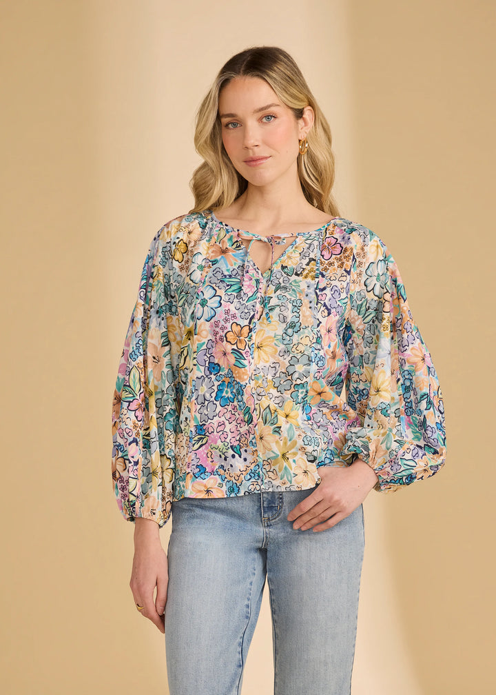 Woman wearing a floral blouse and jeans against a beige background