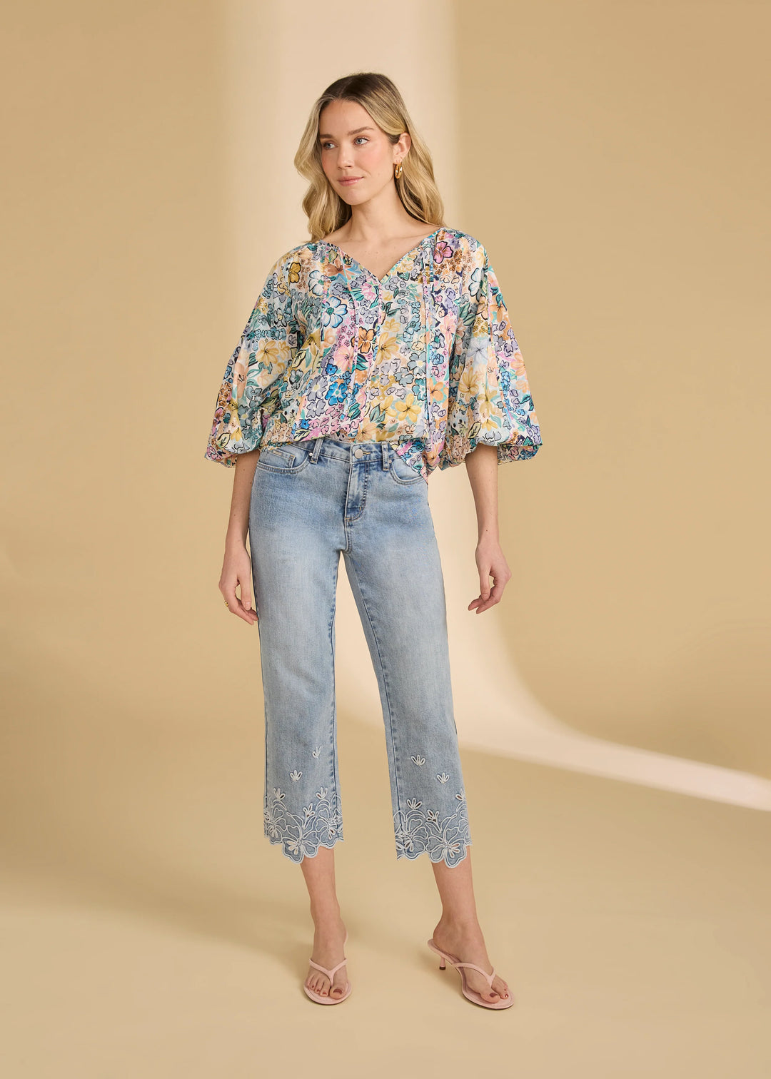 Woman wearing a floral blouse and jeans on a beige background