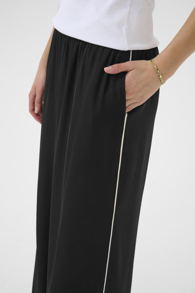 Black pants with a white stripe worn by a person on a plain background