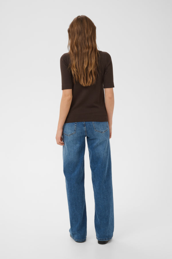 Person wearing a brown shirt and blue jeans on a white background