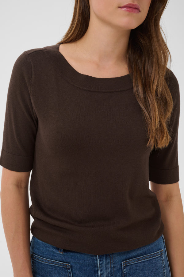 Woman wearing a brown short-sleeve top against a white background