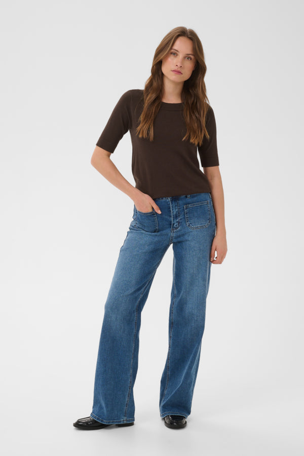 Woman wearing a brown top and blue jeans on a white background
