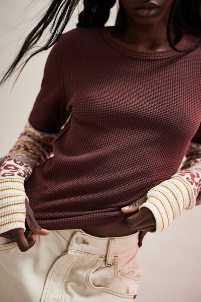 Person wearing a maroon sweater with patterned sleeves against a neutral background