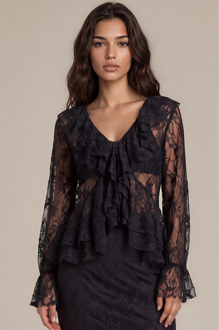 A model wears a black lace long-sleeve midi dress with a ruffled V-neckline and tiered hem, paired with black platform sandals, against a solid beige studio background.
