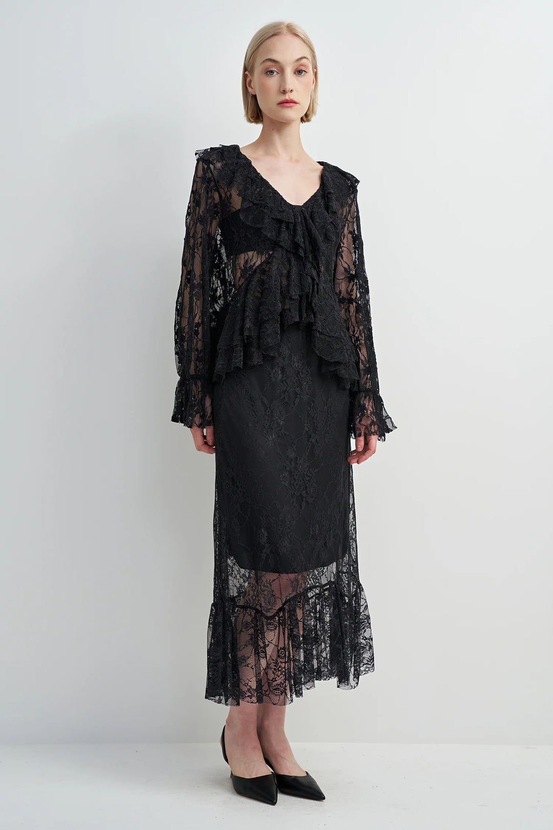 Woman wearing a black lace dress against a white background