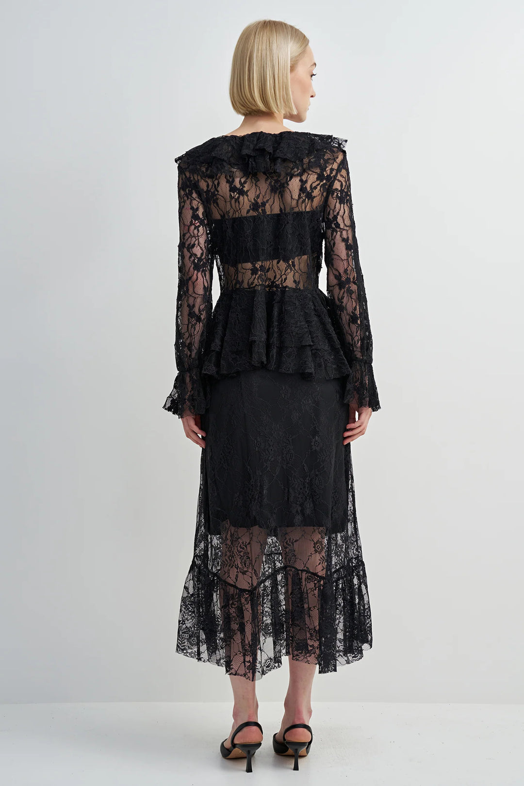 Black lace dress worn by a model on a white background