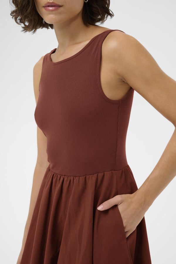Brown sleeveless dress worn by a person on a white background