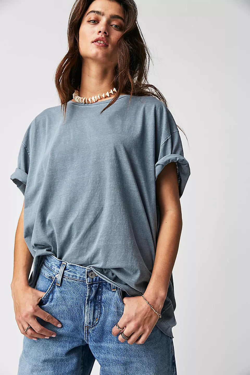 Person wearing a light blue oversized t-shirt and jeans on a white background
