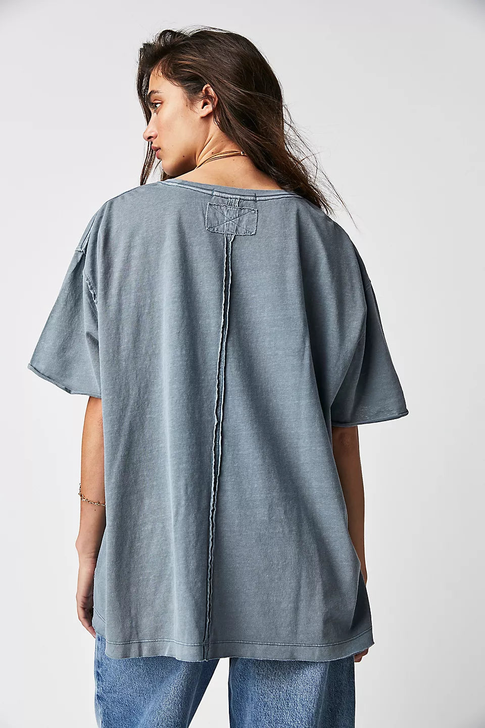 Person wearing a gray oversized t-shirt on a white background