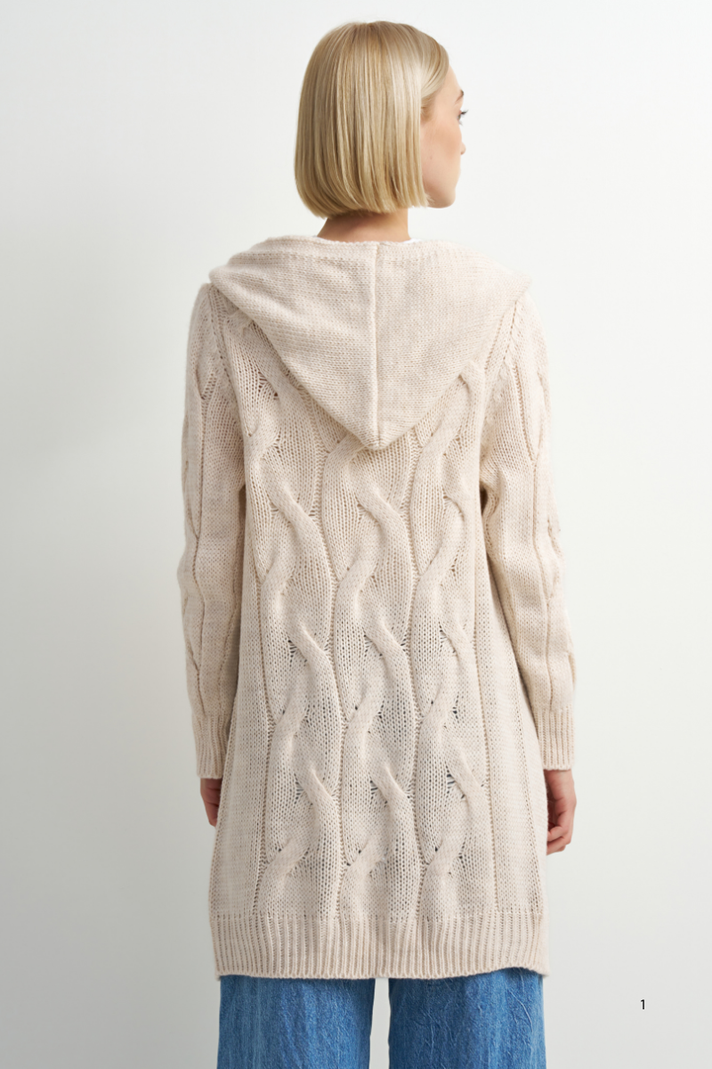 A woman shown from the back wearing a long cream cable-knit hooded cardigan sweater and blue jeans against a plain light background.