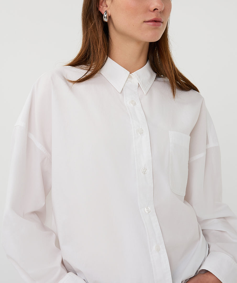 Person wearing a white button-up shirt against a plain background