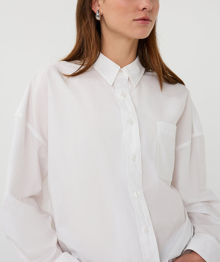 Person wearing a white button-up shirt against a plain background