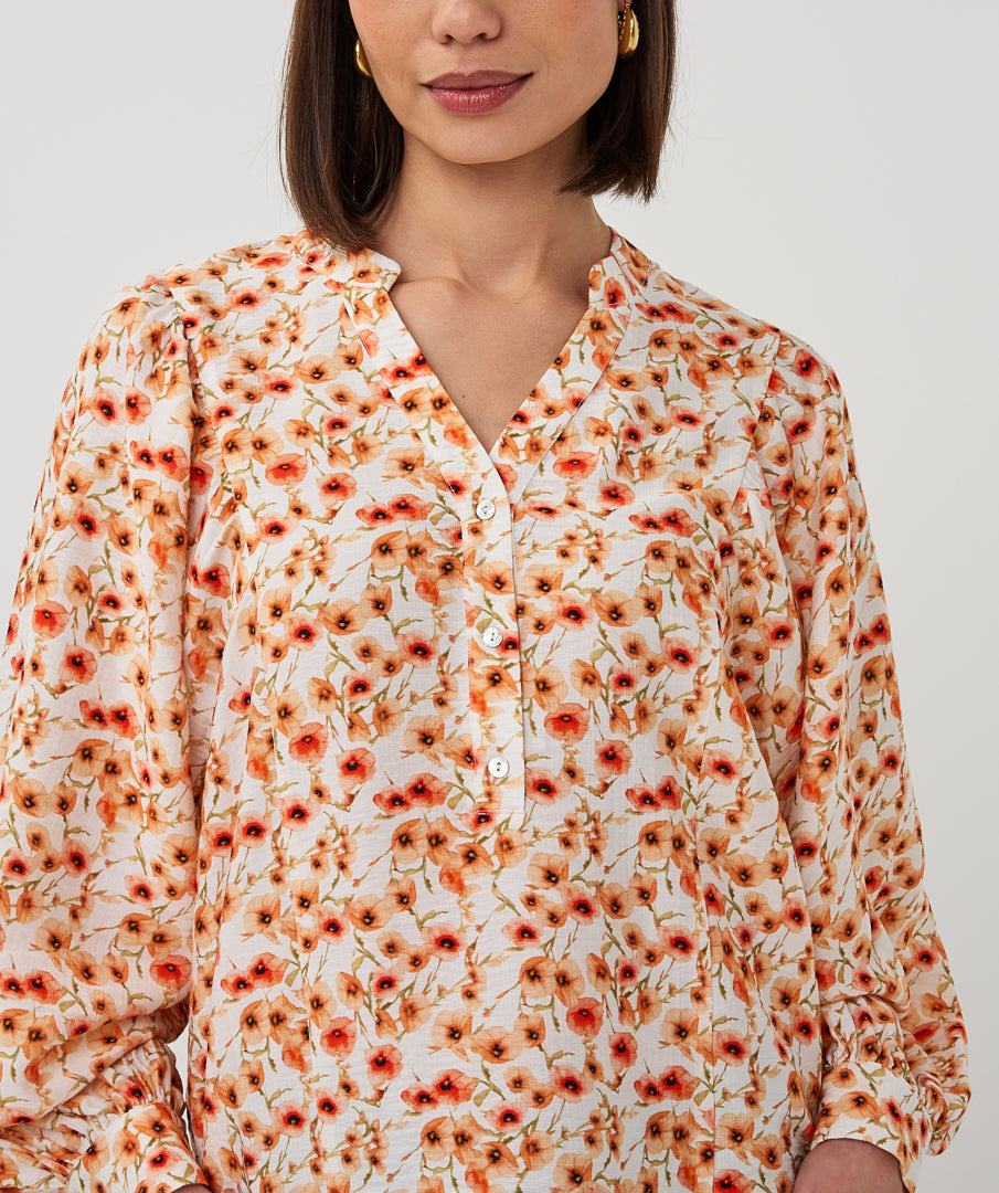 Woman wearing a floral blouse with orange and red flowers on a white background
