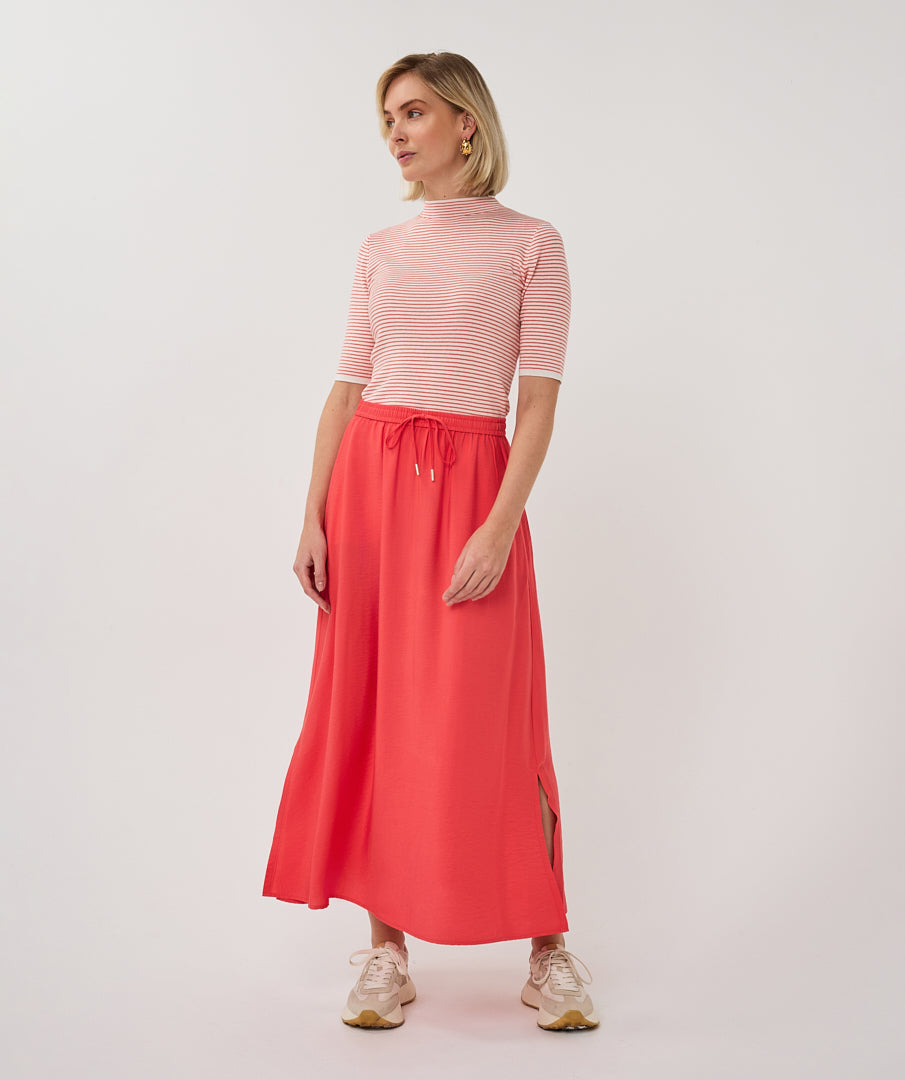 Woman wearing a pink striped top and red skirt on a white background