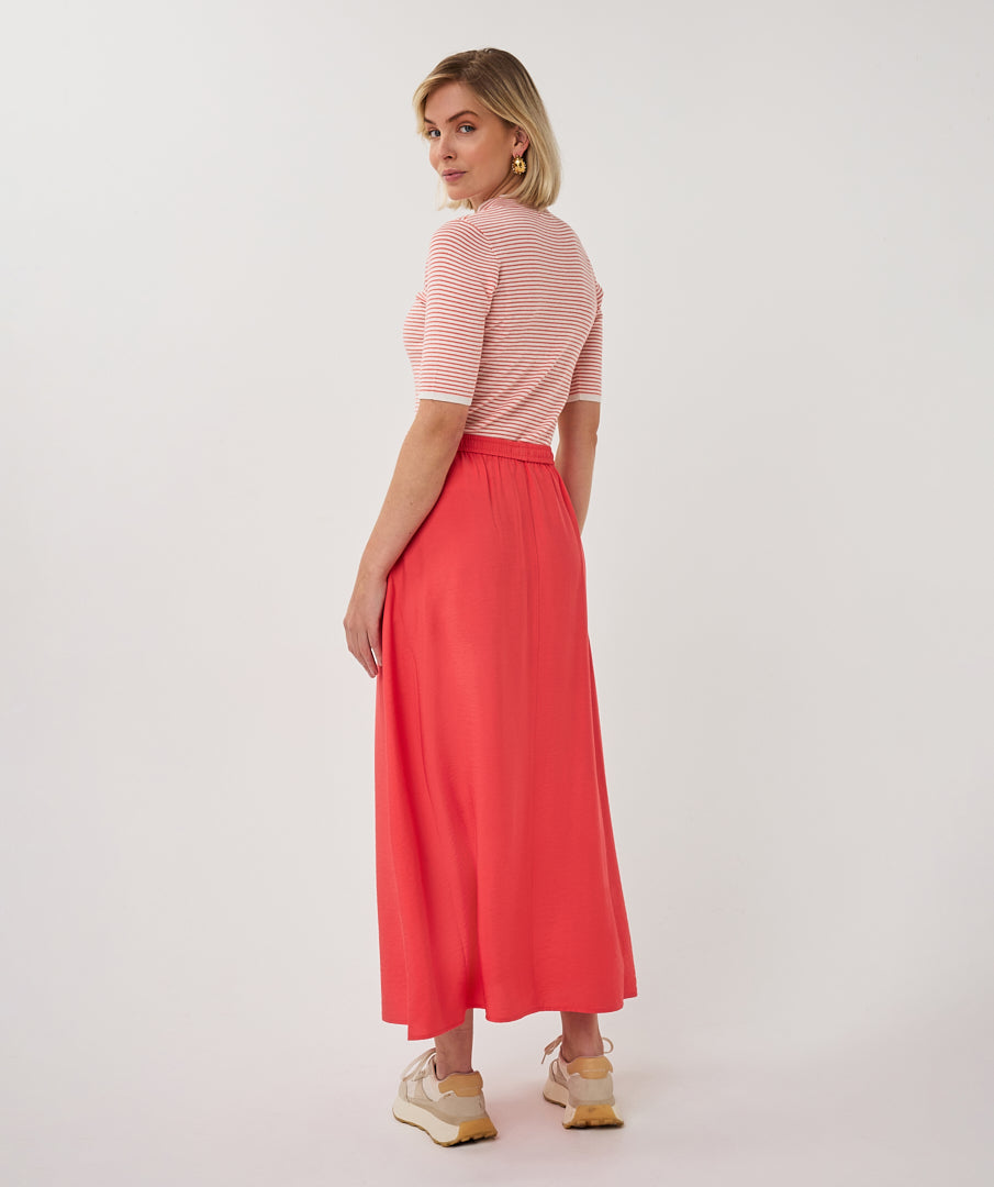 Woman wearing a striped shirt and red skirt on a white background
