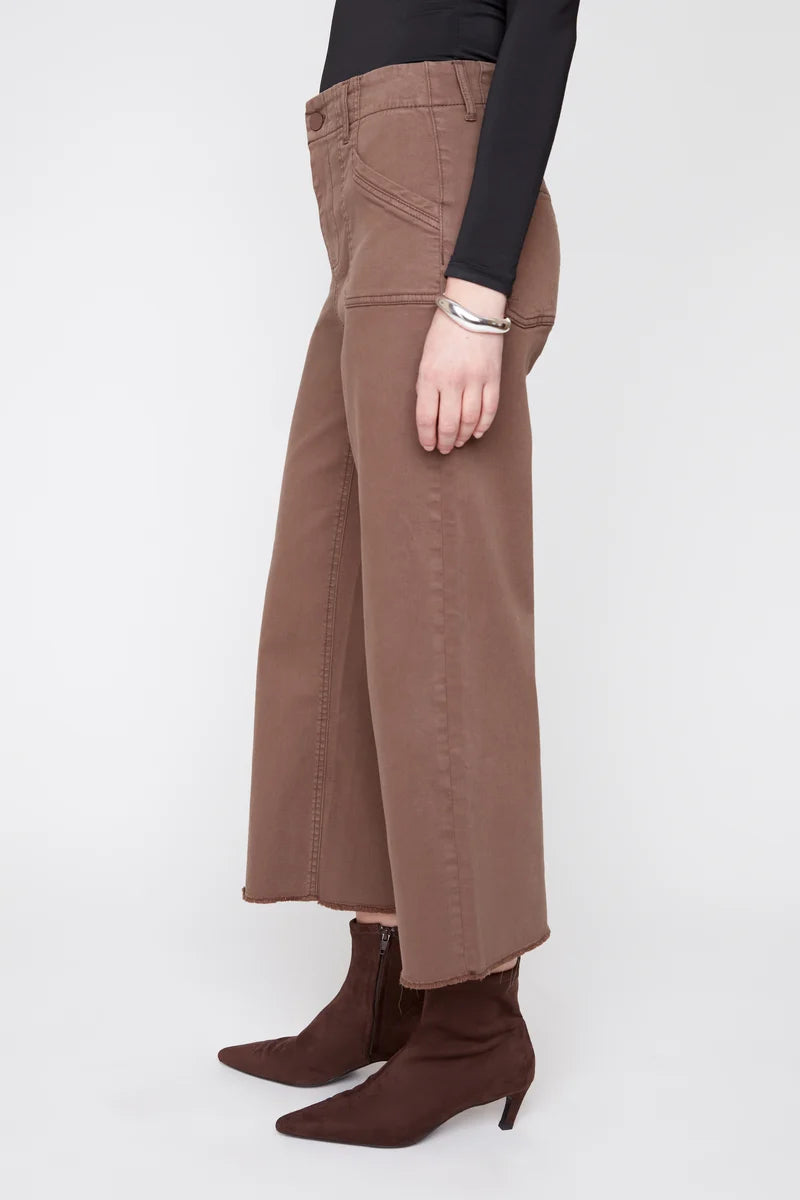 Person wearing brown wide-leg pants and brown boots on a white background