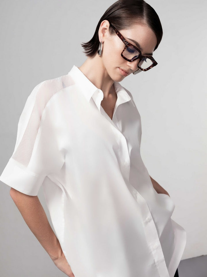 Woman wearing a white shirt against a gray background