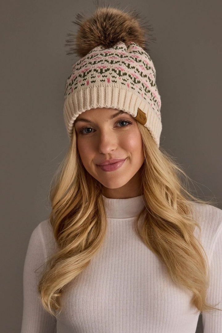 Woman wearing a patterned knit beanie with a pom-pom against a neutral background