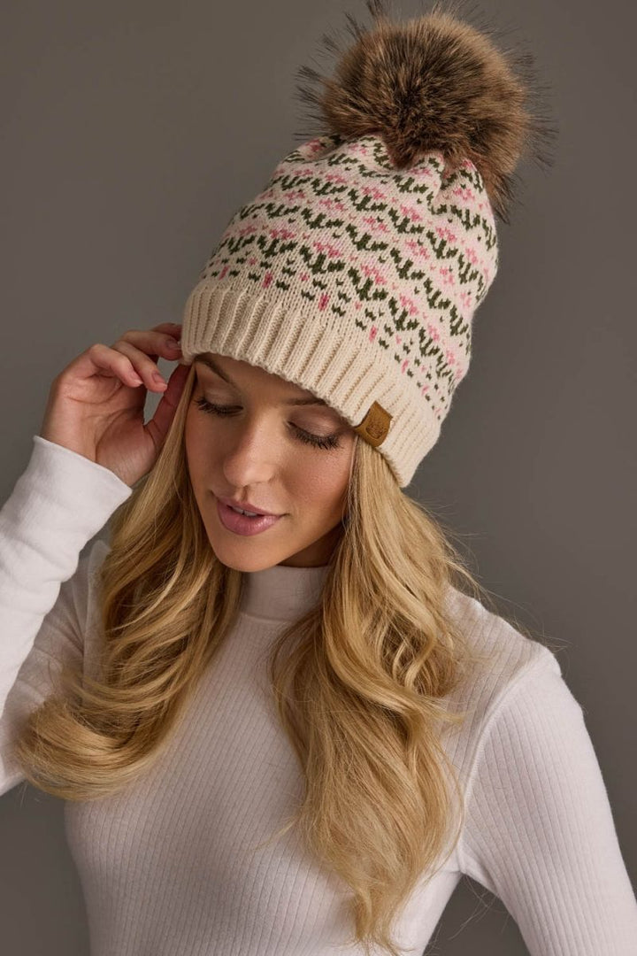 Woman wearing a patterned beanie with a pom-pom on a gray background