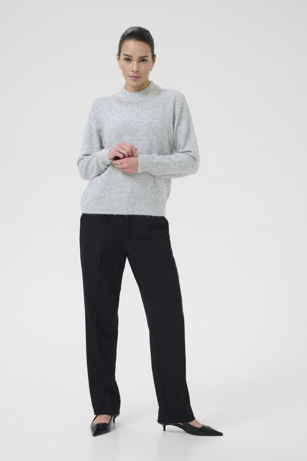 Woman wearing a gray sweater and black pants on a white background