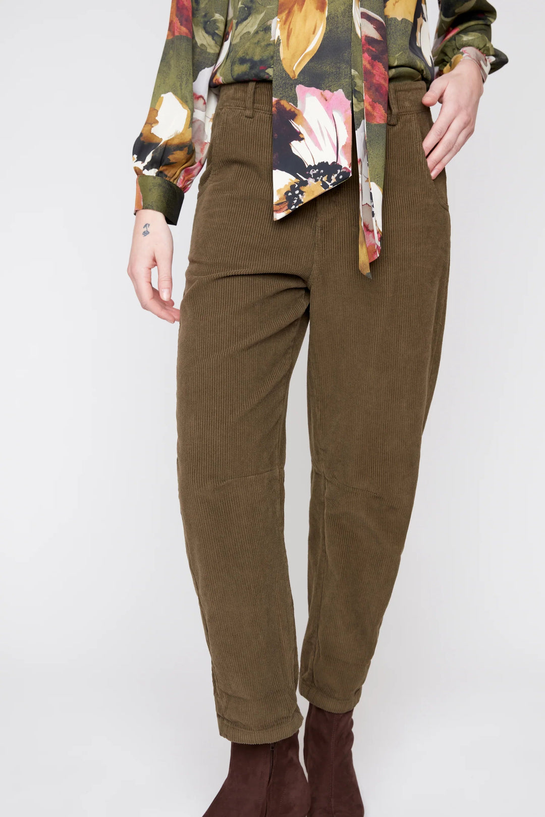 Person wearing brown pants and a colorful top on a white background