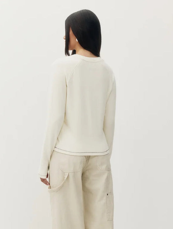 A model shown from the back wearing a cream-colored long-sleeve top and matching cream cargo pants against a plain white studio background.