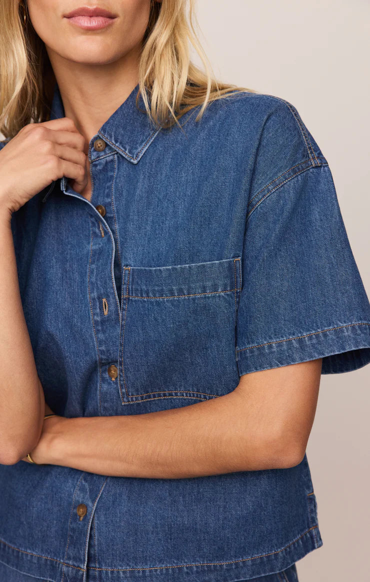 Woman wearing a blue denim shirt against a neutral background