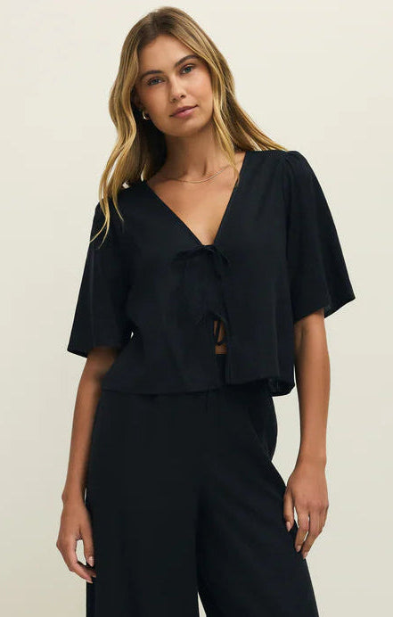 Woman wearing a black outfit with wide-leg pants on a white background