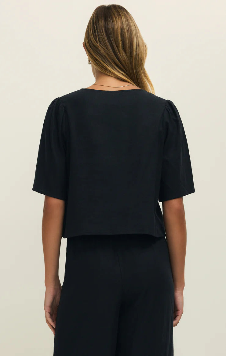 Person wearing a black top and pants on a beige background