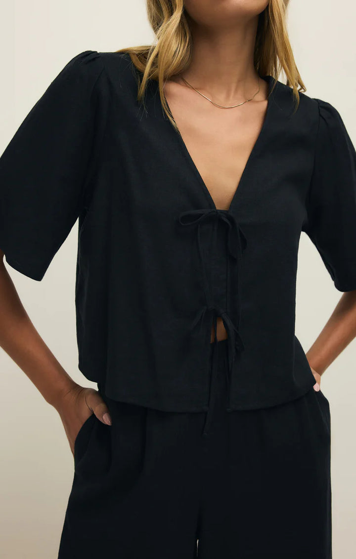 Person wearing a black outfit with a plunging neckline against a neutral background