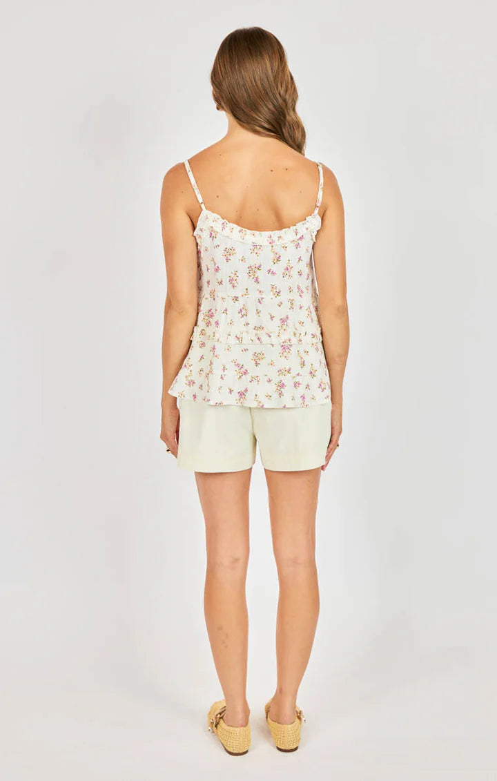 Woman wearing a floral top and shorts on a white background