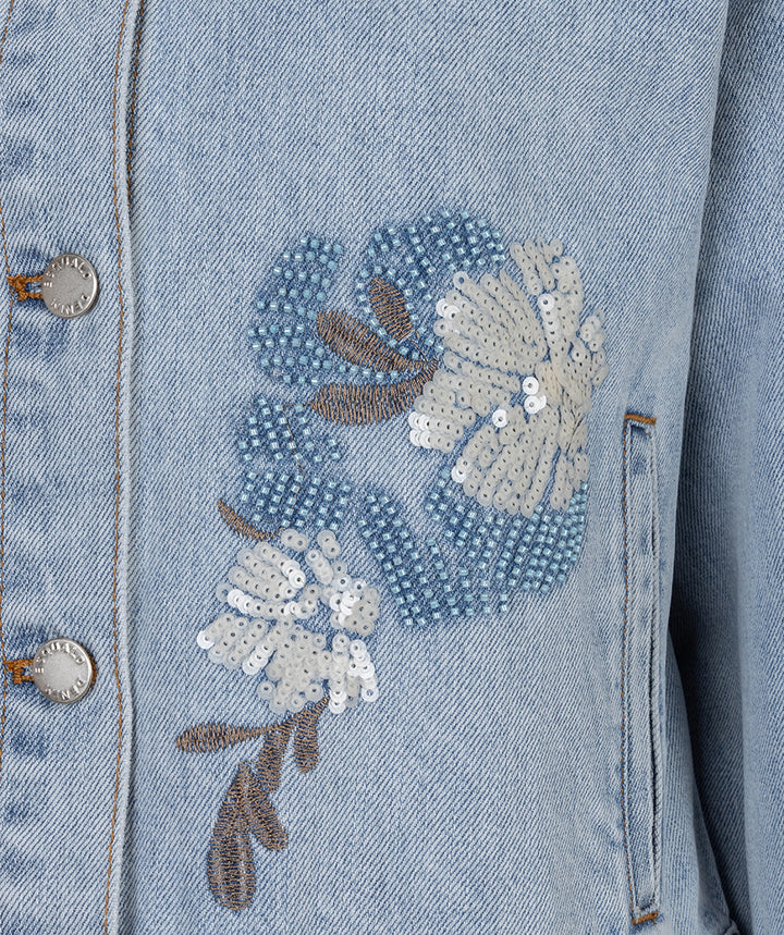 Denim jacket with floral sequin embroidery on a light blue background