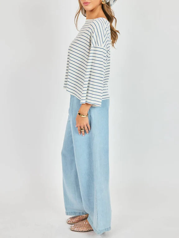Woman wearing a striped shirt and light blue wide-leg pants on a white background