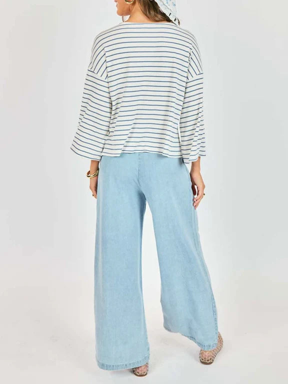Person wearing a striped shirt and light blue wide-leg jeans on a white background