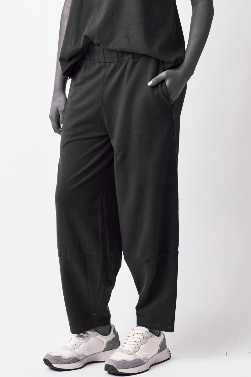 Person wearing black pants and white sneakers on a white background