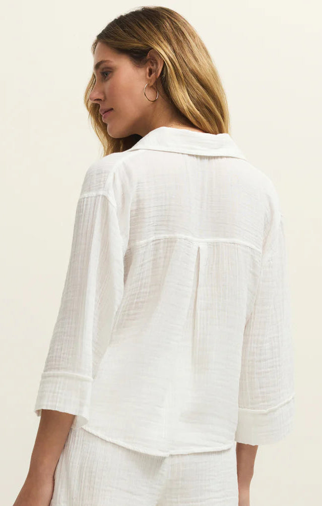 Woman wearing a white outfit with a textured pattern on a plain background