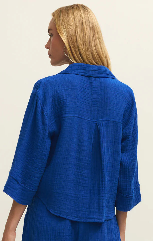 Woman wearing a blue textured outfit with a jacket and shorts on a beige background