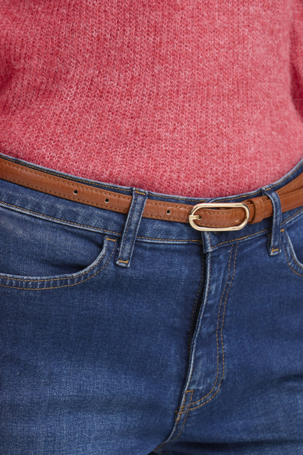 Close-up of blue jeans with a brown belt and red shirt.