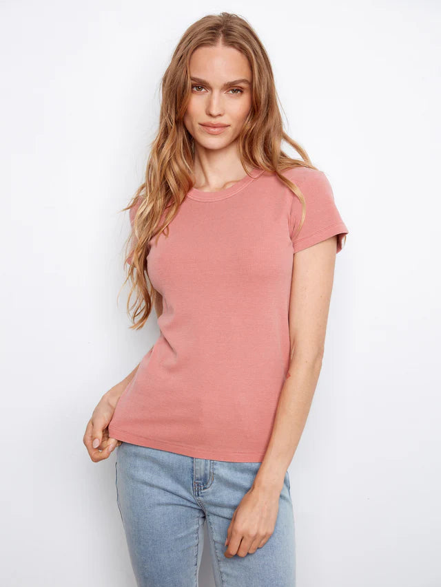 Woman wearing a pink t-shirt and blue jeans against a white background