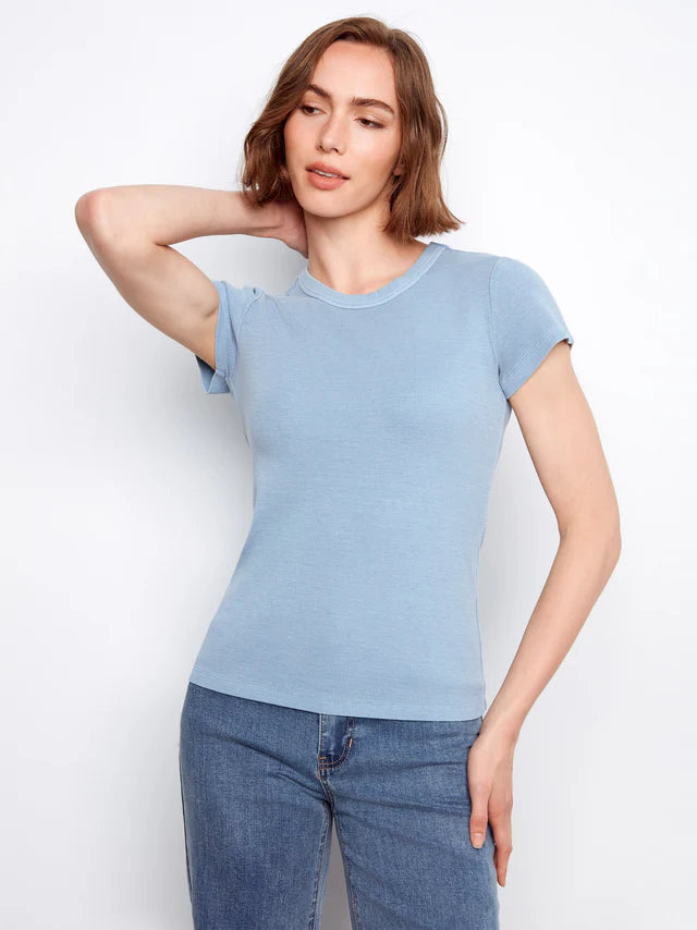 Woman wearing a light blue t-shirt and jeans against a white background