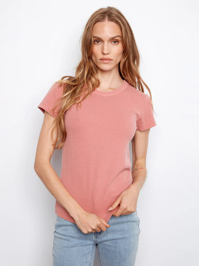 Woman wearing a pink t-shirt and blue jeans against a white background