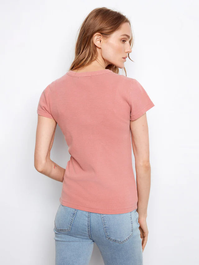 Woman wearing a pink t-shirt and blue jeans against a white background