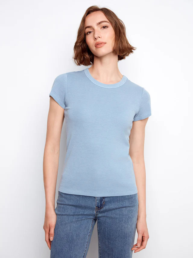 Woman wearing a light blue t-shirt and jeans against a white background