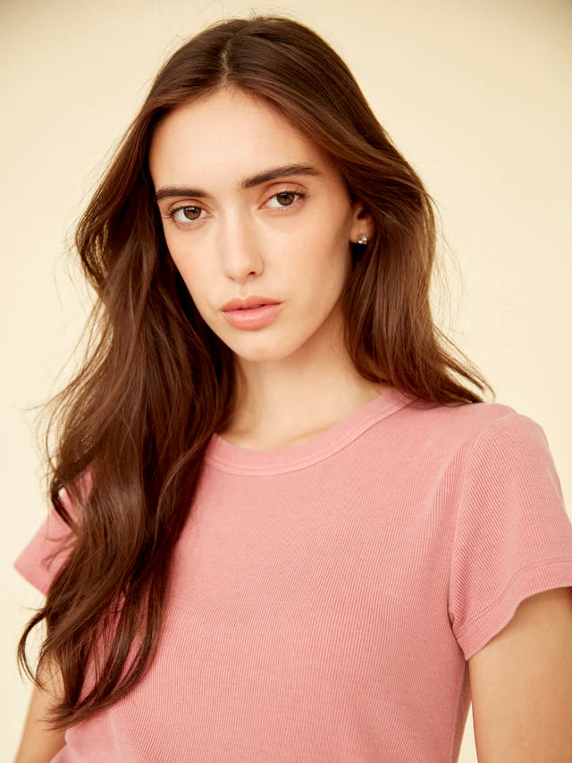 Woman wearing a pink shirt against a beige background