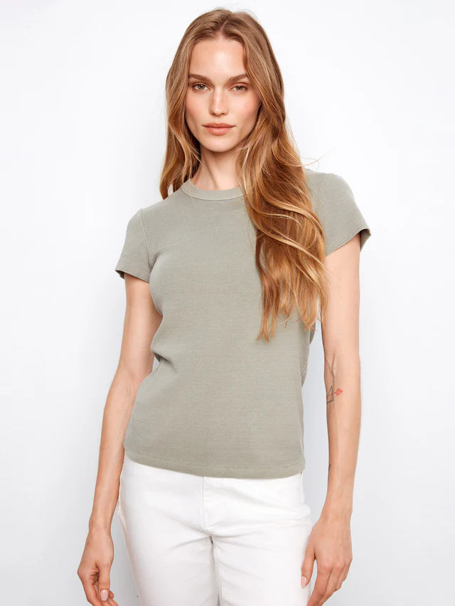 Woman wearing a green t-shirt and white pants against a white background