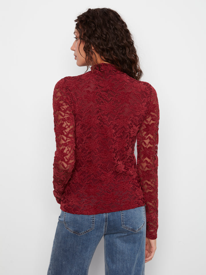 A woman shown from the back wearing a long-sleeve, high-neck burgundy lace top and blue jeans against a plain white background.