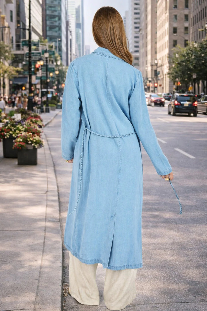Person wearing a light blue denim dress walking on a city street.